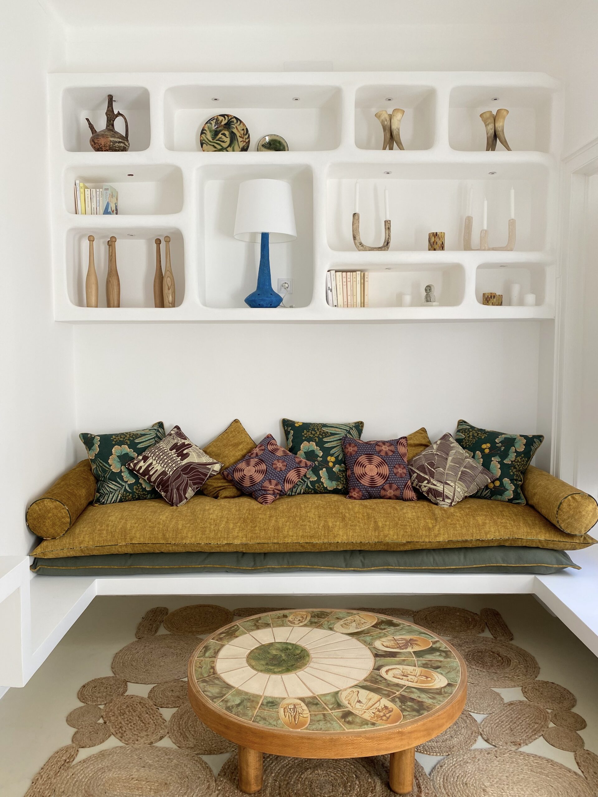 canapé jaune avec coussins colorés et une bibliothèque blanche avec des éléments de décoration